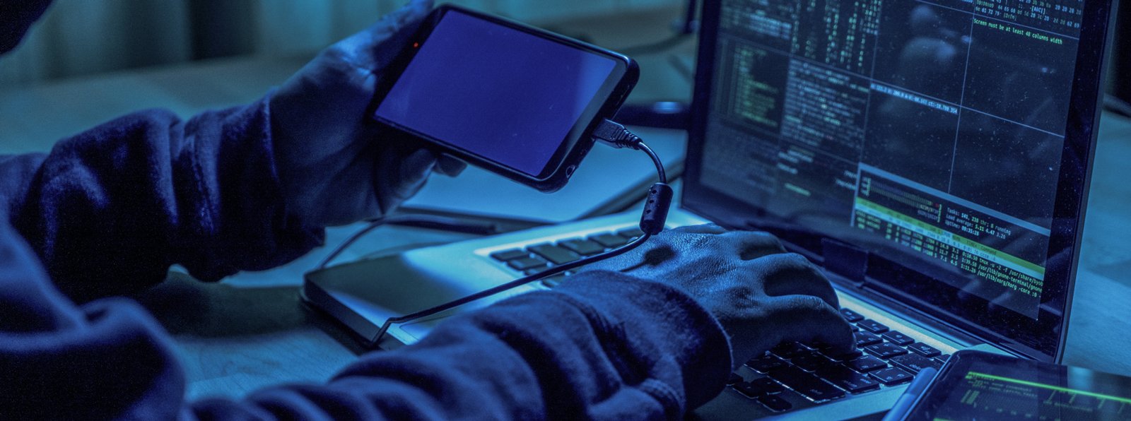hacker with phone and laptop