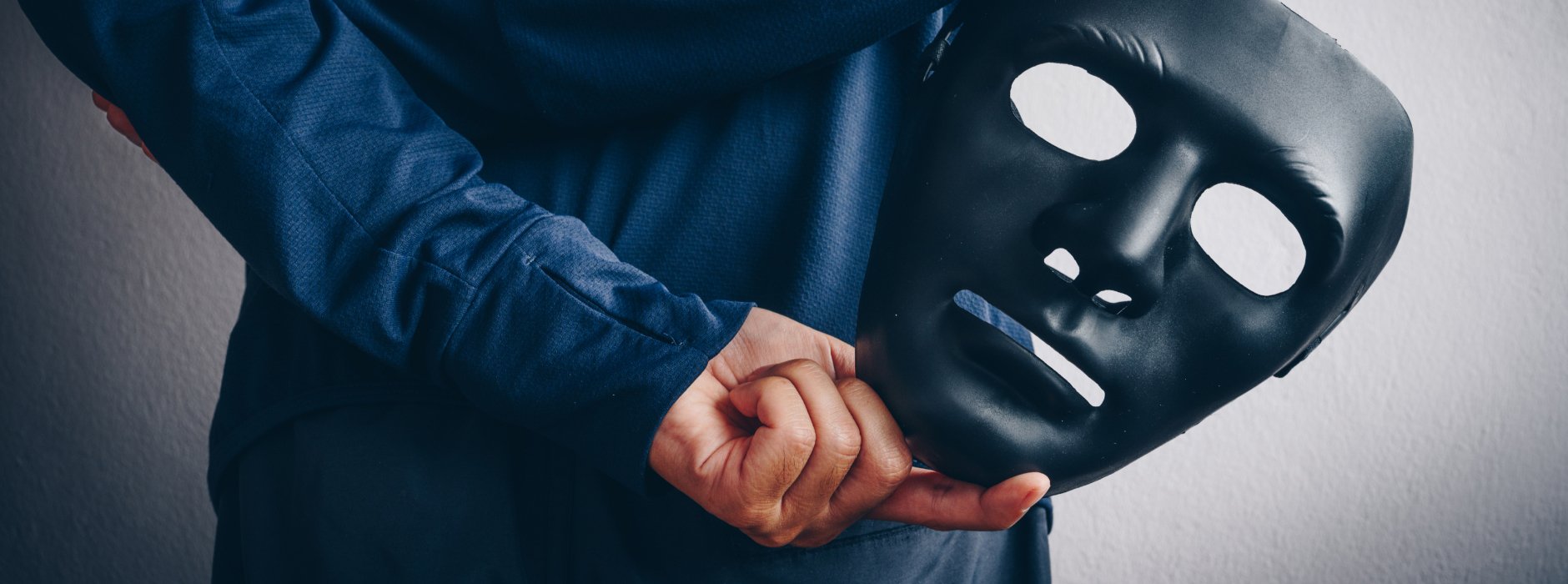 man holding mask behind his back