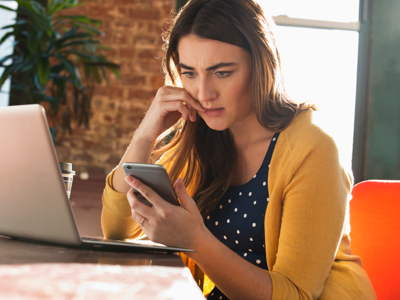 women in front of laptop looking at phone