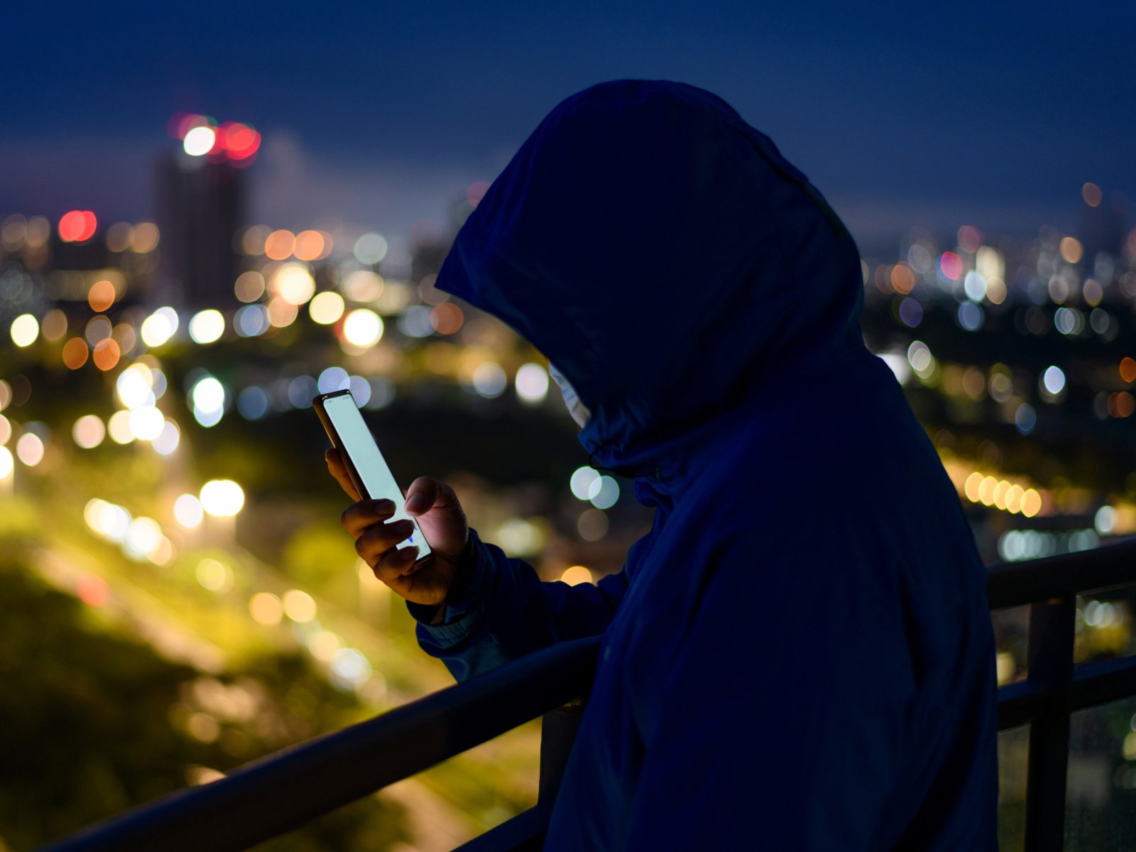 man in hoodie looking at phone