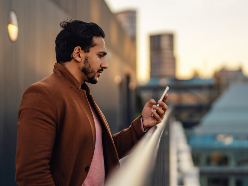 Man on a balcony looking at his phone