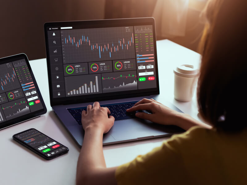 someone trading forex sitting at a desk with multiple screens showing price charts