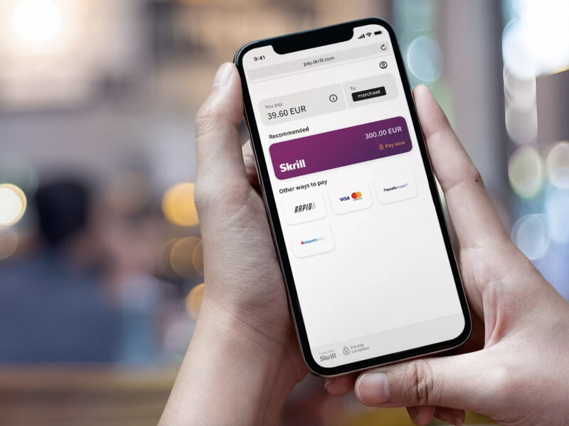 someone looking at their phone with the screen showing someone paying a merchant with Skrill