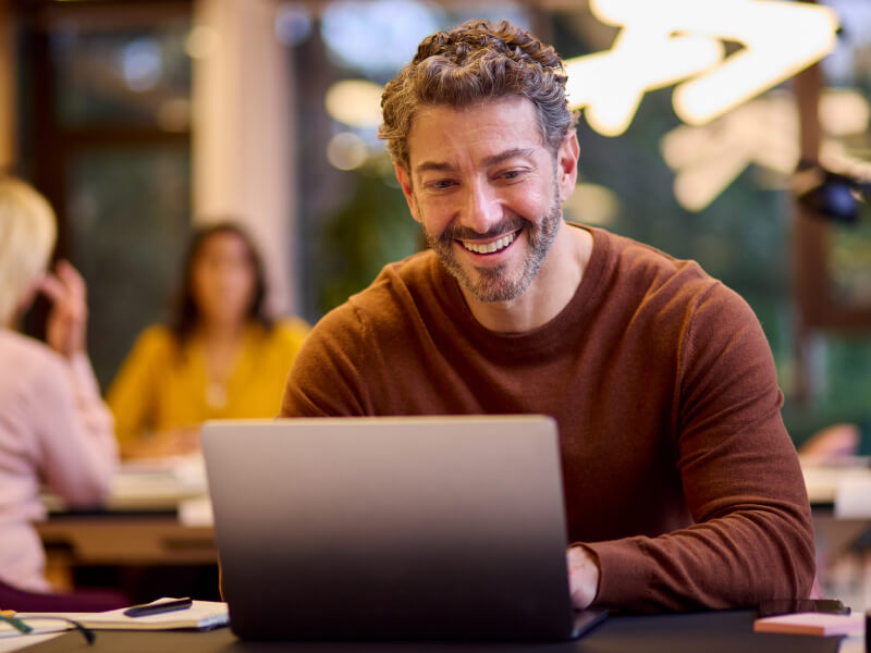 someone looking at their laptop thoughtfully, as though researching the best forex trading platforms