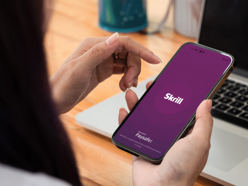 someone looking at their phone open to the Skrill splash app