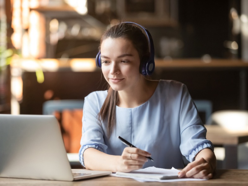 a girl learning from a laptop and writing down important notes