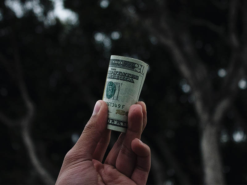 hand holding roll of dollars