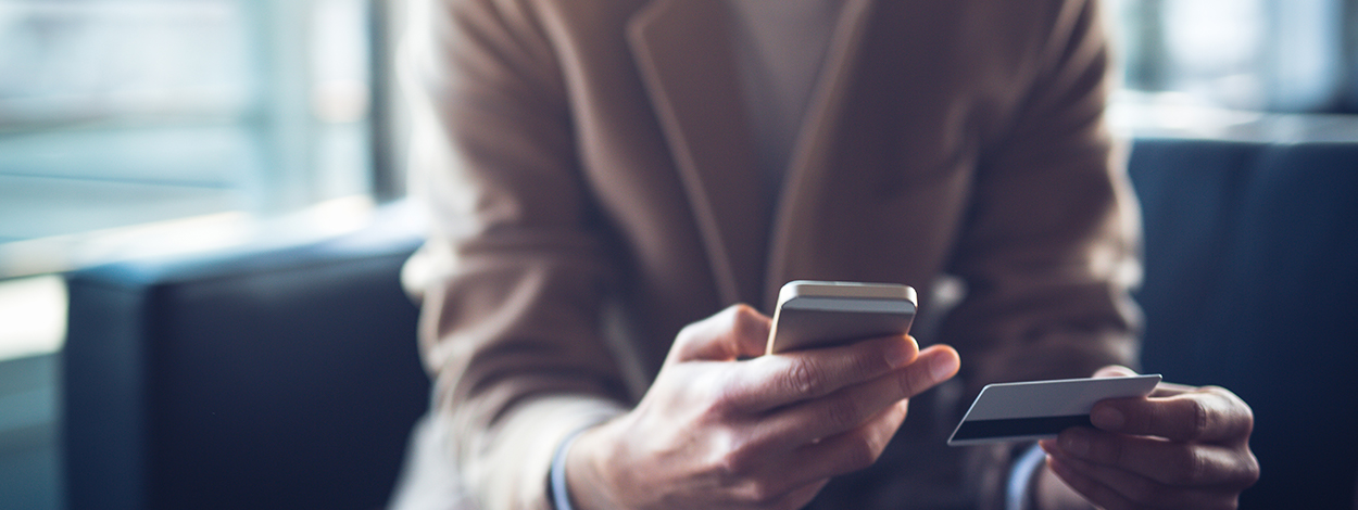 Person holding phone and plastic card, using Skrill payments gateway at our partners online business