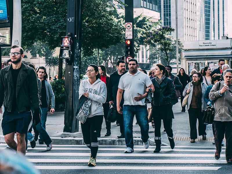 Busy crowded street in modern Brazilian city with people crossing the crosswalk