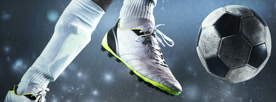soccer player kicking the ball on the field on a rainy night