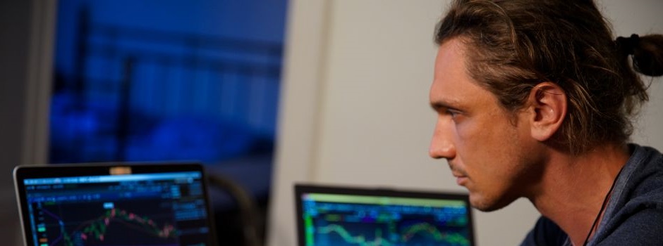 man staring at a two desktops with graphs