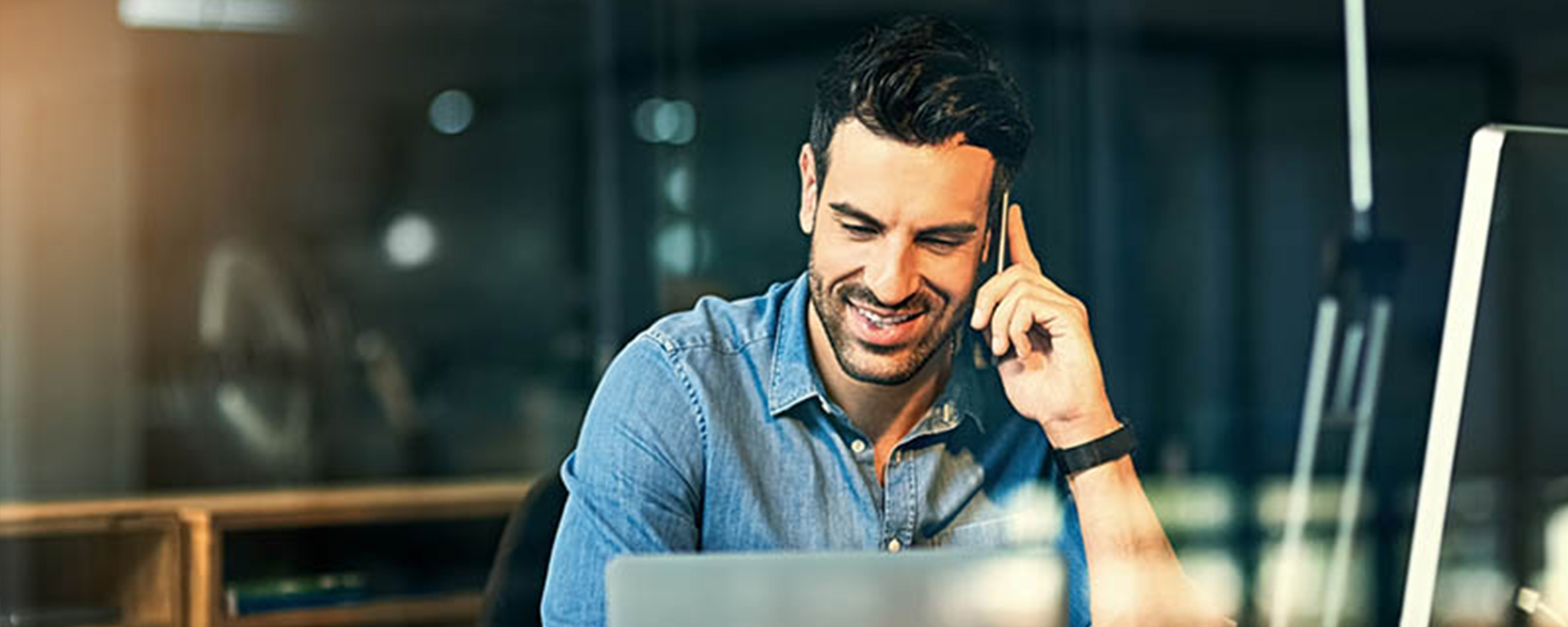 man in front of laptop talking on a phone
