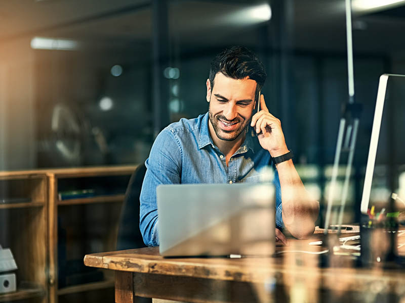 man in front of laptop talking on a phone