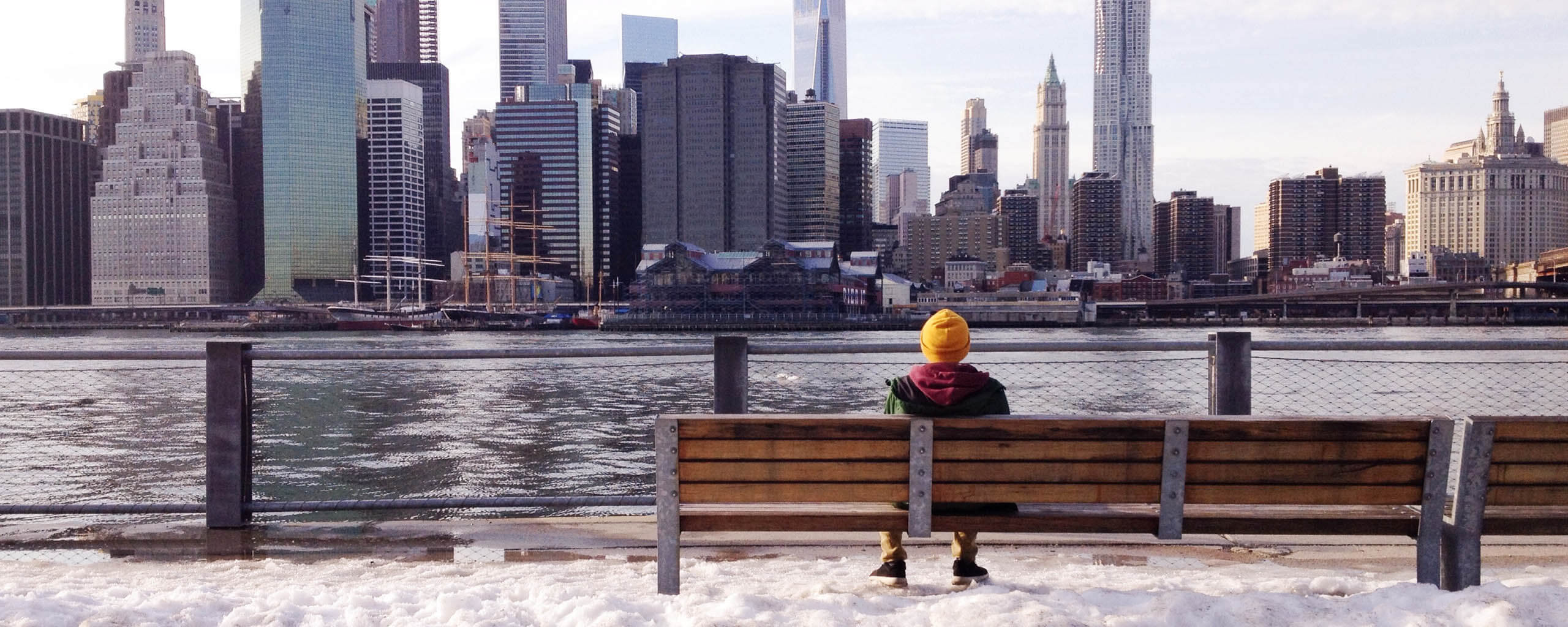 man on a bench looking at a city river