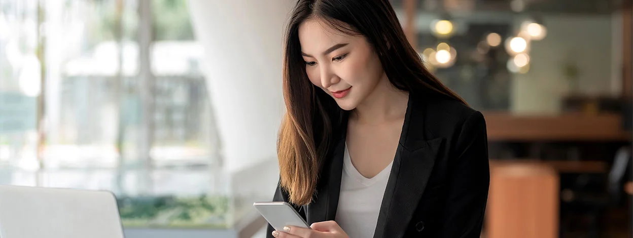 a smiling woman using Skrill Quick checkout on her mobile in a light room