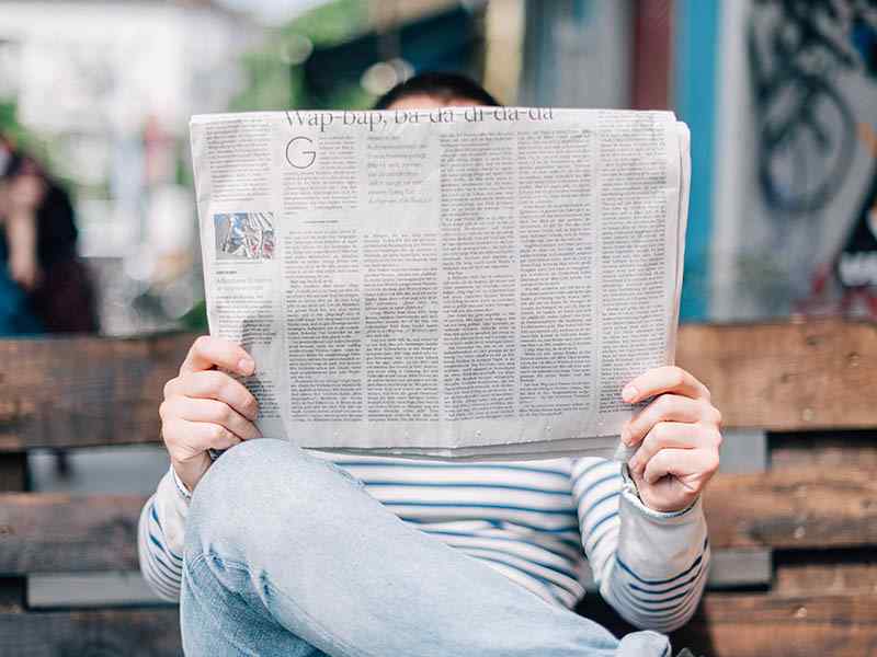 man on a bench reading newspaper