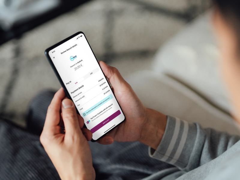 someone holding a mobile phone with Skrill app open